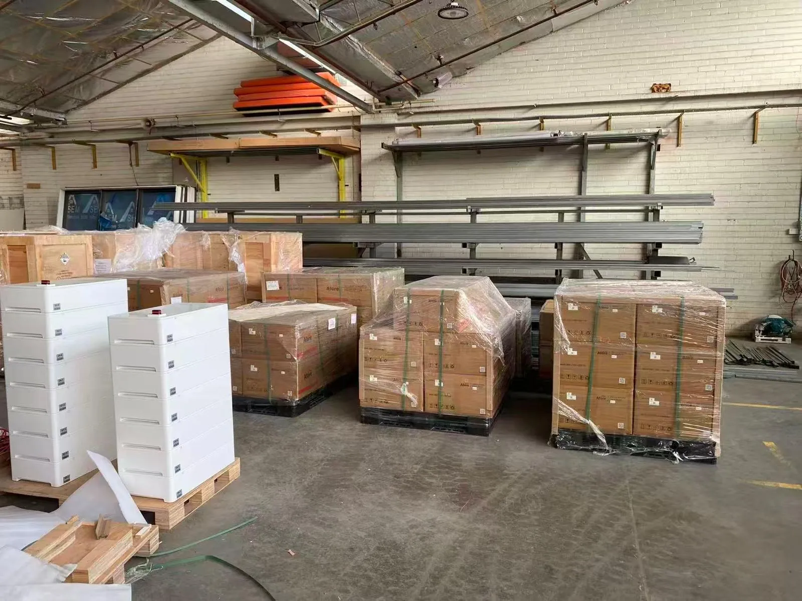 Stacked white battery modules beside pallets of boxed Afore inverters in a warehouse